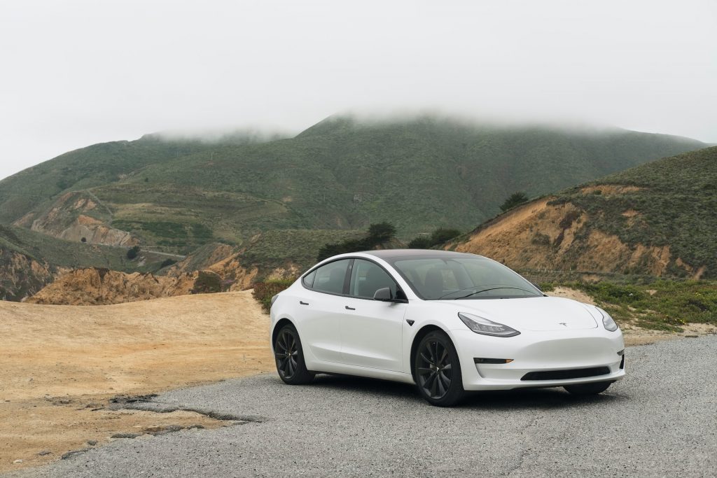white tesla parked in front of mountains
